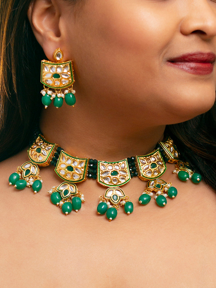 Close-up of a woman wearing an ornate traditional (Gold Polish) Dark Green Choker jewellery set and earrings with Pearl, Crystal stones, Kundan, Colored Stones and Tumble Beads. Mehendi ceremony look completed with a handcrafted Kundan jewelry set. Wedding celebration look enhanced with a statement Kundan necklace.