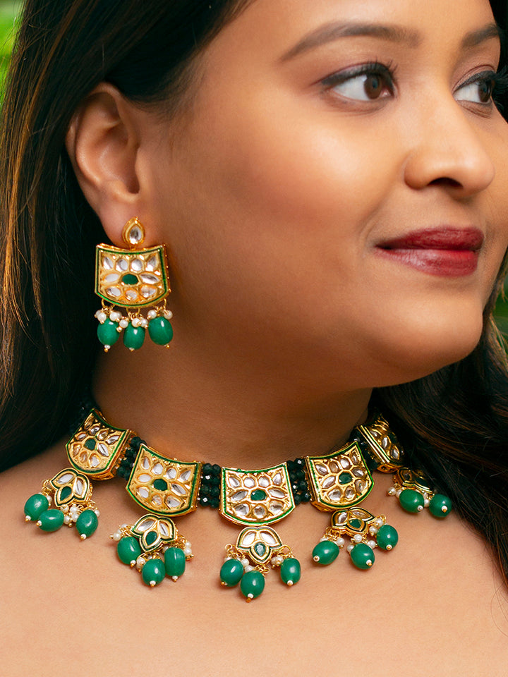 Close-up of a woman wearing an ornate traditional (Gold Polish) Dark Green Choker jewellery set and earrings with Pearl, Crystal stones, Kundan, Colored Stones and Tumble Beads. Mehendi ceremony look completed with a handcrafted Kundan jewelry set. Wedding celebration look enhanced with a statement Kundan necklace.