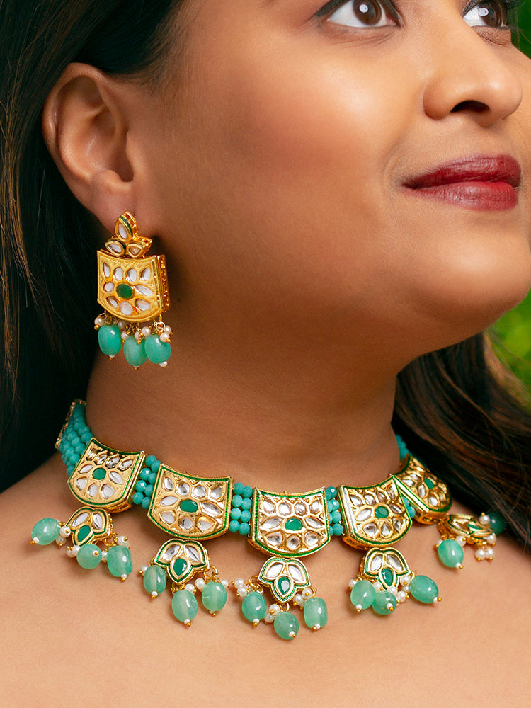 Close-up of a woman wearing an ornate traditional (Gold Polish) Mint Green Choker jewellery set and earrings with Pearl, Crystal stones, Kundan, Colored Stones and Tumble Beads. Mehendi ceremony look completed with a handcrafted Kundan jewelry set. Wedding celebration look enhanced with a statement Kundan necklace.