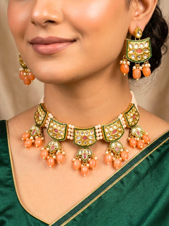 Close-up of a woman wearing an ornate traditional (Gold Polish) Peach Choker jewellery set and earrings with Pearl, Crystal stones, Kundan, Colored Stones and Tumble Beads. Mehendi ceremony look completed with a handcrafted Kundan jewelry set. Wedding celebration look enhanced with a statement Kundan necklace.