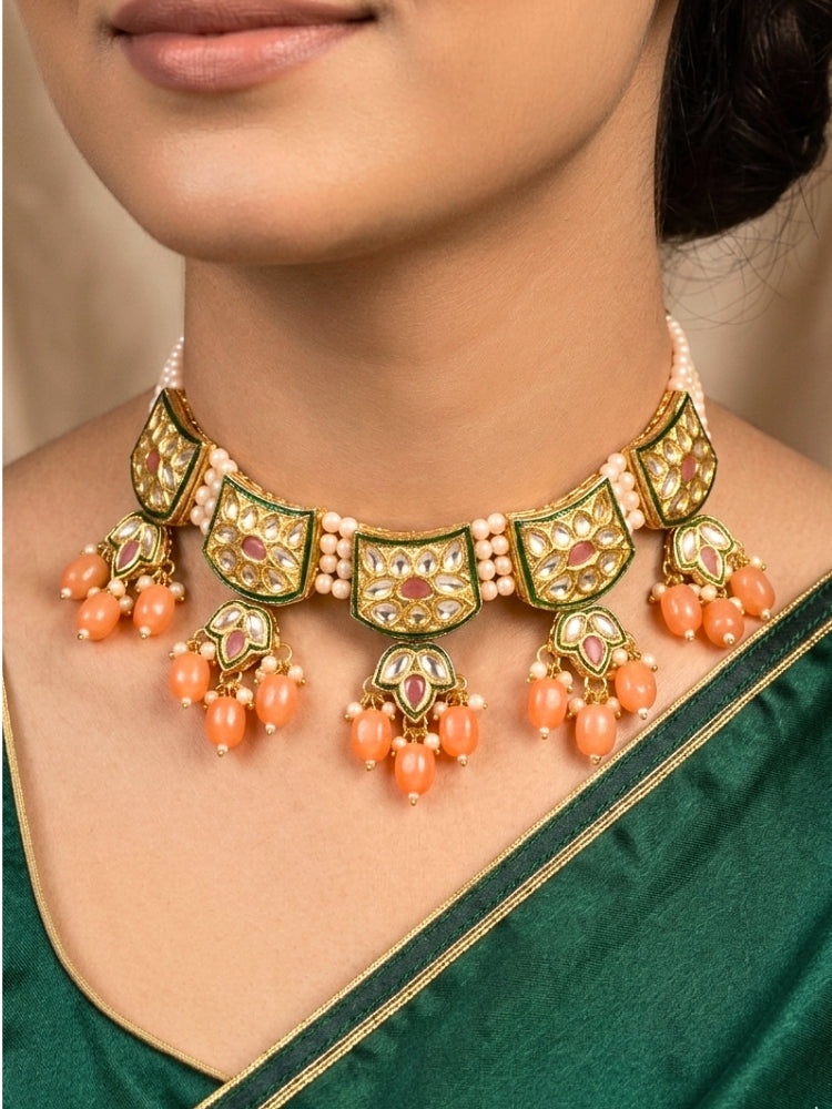 Close-up of a woman wearing an ornate traditional (Gold Polish) Peach Choker jewellery set and earrings with Pearl, Crystal stones, Kundan, Colored Stones and Tumble Beads. Mehendi ceremony look completed with a handcrafted Kundan jewelry set. Wedding celebration look enhanced with a statement Kundan necklace.