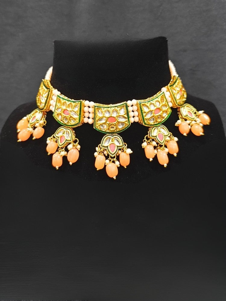 Close-up of an ornate traditional (Gold Polish) Peach Choker jewellery set and earrings with Pearl, Crystal stones, Kundan, Colored Stones and Tumble Beads. Mehendi ceremony look completed with a handcrafted Kundan jewelry set. Wedding celebration look enhanced with a statement Kundan necklace.