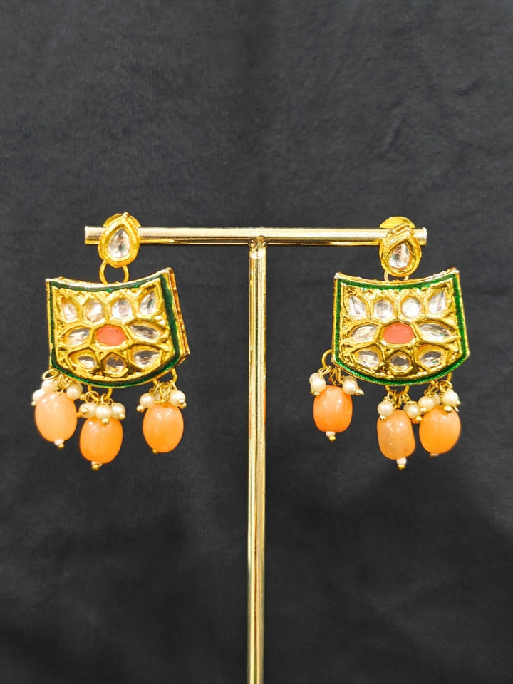 Close-up of an ornate traditional (Gold Polish) Peach Choker jewellery set and earrings with Pearl, Crystal stones, Kundan, Colored Stones and Tumble Beads. Mehendi ceremony look completed with a handcrafted Kundan jewelry set. Wedding celebration look enhanced with a statement Kundan necklace.