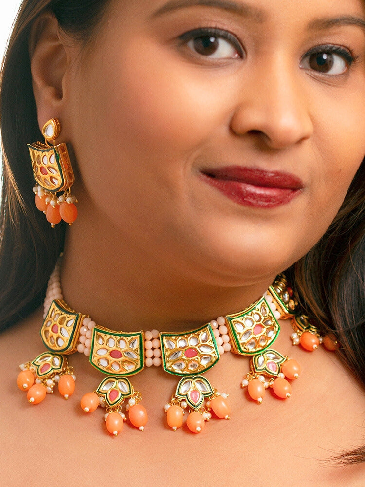Close-up of a woman wearing an ornate traditional (Gold Polish) Peach Choker jewellery set and earrings with Pearl, Crystal stones, Kundan, Colored Stones and Tumble Beads. Mehendi ceremony look completed with a handcrafted Kundan jewelry set. Wedding celebration look enhanced with a statement Kundan necklace.