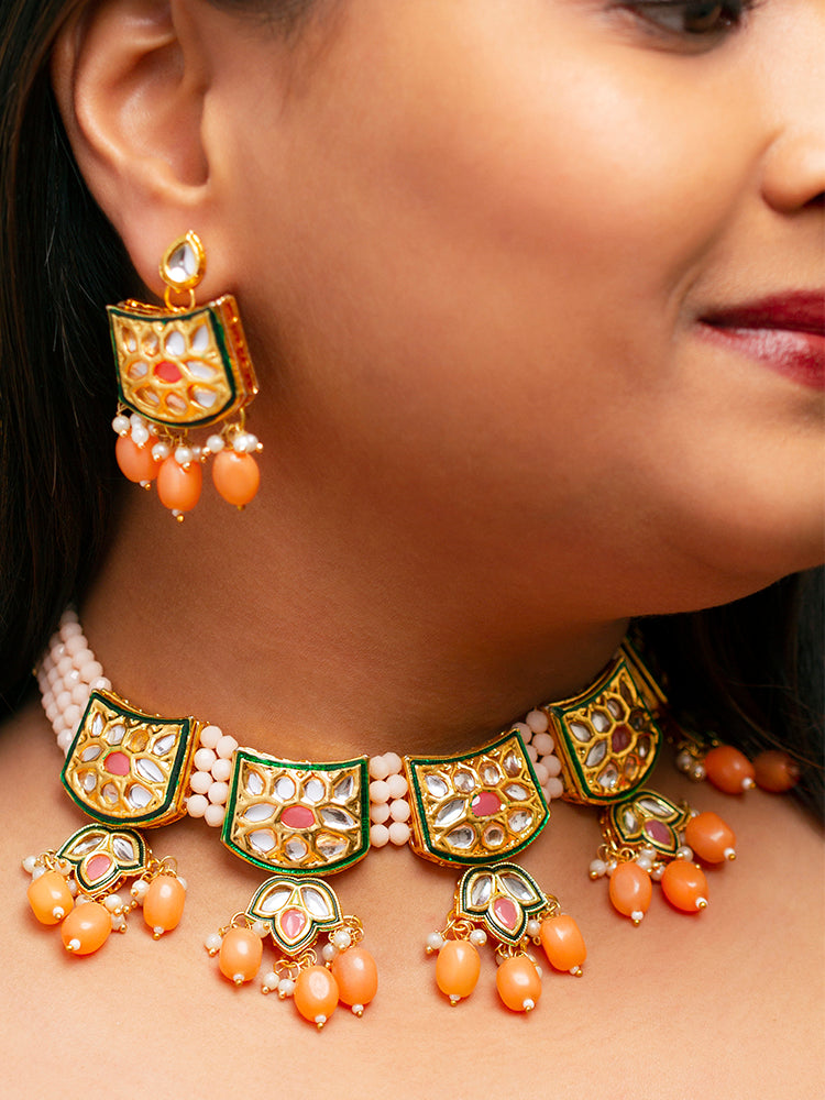 Close-up of a woman wearing an ornate traditional (Gold Polish) Peach Choker jewellery set and earrings with Pearl, Crystal stones, Kundan, Colored Stones and Tumble Beads. Mehendi ceremony look completed with a handcrafted Kundan jewelry set. Wedding celebration look enhanced with a statement Kundan necklace.