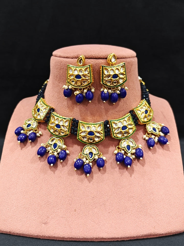 Close-up of an ornate traditional (Gold Polish) Purple Choker jewellery set and earrings with Pearl, Crystal stones, Kundan, Colored Stones and Tumble Beads. Mehendi ceremony look completed with a handcrafted Kundan jewelry set. Wedding celebration look enhanced with a statement Kundan necklace.