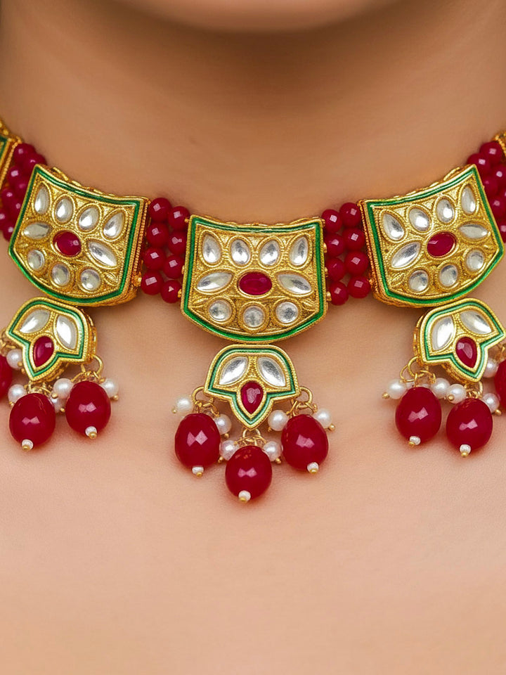 Close-up of a woman wearing an ornate traditional (Gold Polish) Red Choker jewellery set and earrings with Pearl, Crystal stones, Kundan, Colored Stones and Tumble Beads. Mehendi ceremony look completed with a handcrafted Kundan jewelry set. Wedding celebration look enhanced with a statement Kundan necklace.