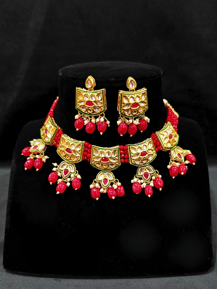 Close-up of an ornate traditional (Gold Polish) Red Choker jewellery set and earrings with Pearl, Crystal stones, Kundan, Colored Stones and Tumble Beads. Mehendi ceremony look completed with a handcrafted Kundan jewelry set. Wedding celebration look enhanced with a statement Kundan necklace.