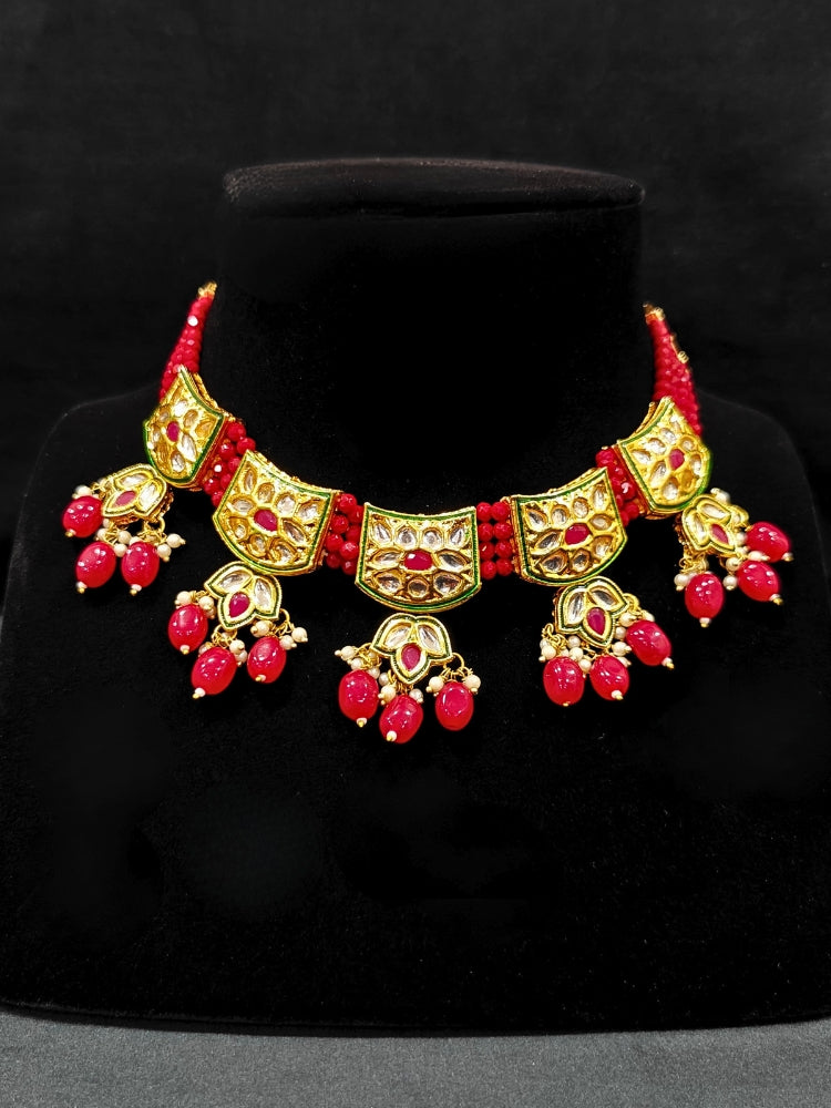 Close-up of a woman wearing an ornate traditional (Gold Polish) Red Choker jewellery set and earrings with Pearl, Crystal stones, Kundan, Colored Stones and Tumble Beads. Mehendi ceremony look completed with a handcrafted Kundan jewelry set. Wedding celebration look enhanced with a statement Kundan necklace.