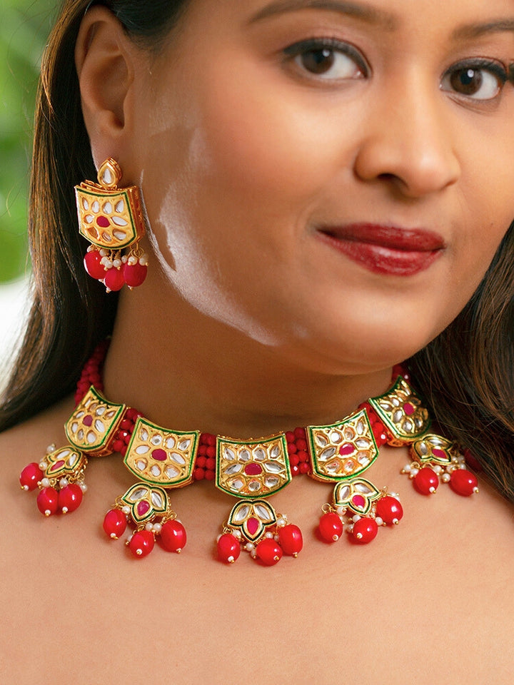 Close-up of a woman wearing an ornate traditional (Gold Polish) Red Choker jewellery set and earrings with Pearl, Crystal stones, Kundan, Colored Stones and Tumble Beads. Mehendi ceremony look completed with a handcrafted Kundan jewelry set. Wedding celebration look enhanced with a statement Kundan necklace.