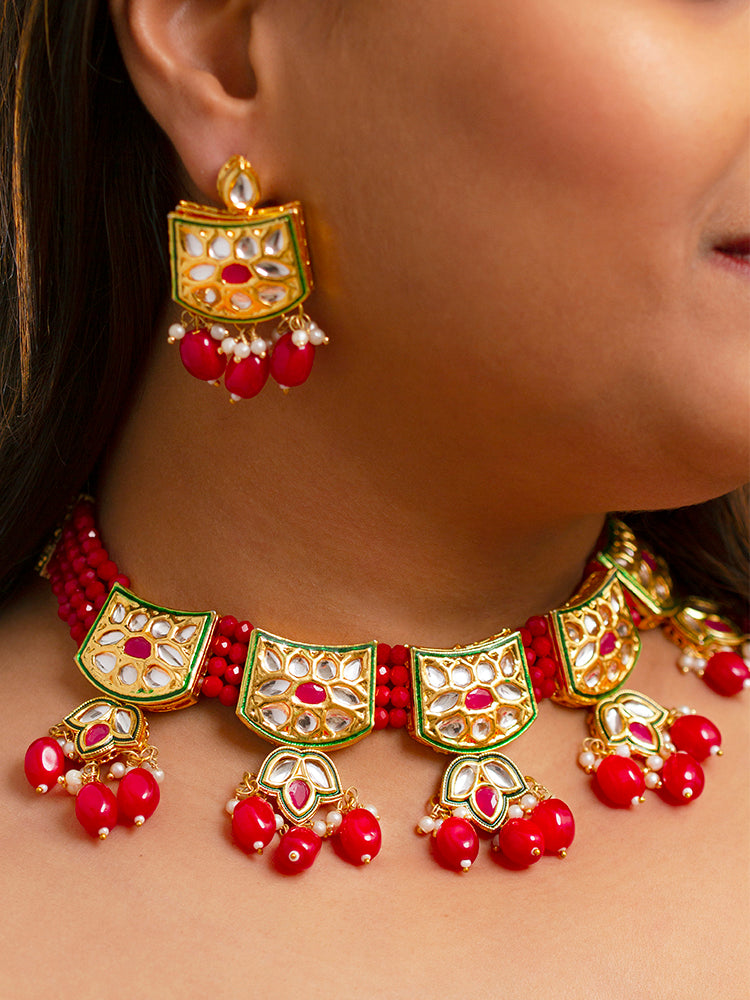 Close-up of a woman wearing an ornate traditional (Gold Polish) Red Choker jewellery set and earrings with Pearl, Crystal stones, Kundan, Colored Stones and Tumble Beads. Mehendi ceremony look completed with a handcrafted Kundan jewelry set. Wedding celebration look enhanced with a statement Kundan necklace.