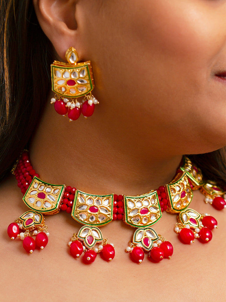 Close-up of a woman wearing an ornate traditional (Gold Polish) Red Choker jewellery set and earrings with Pearl, Crystal stones, Kundan, Colored Stones and Tumble Beads. Mehendi ceremony look completed with a handcrafted Kundan jewelry set. Wedding celebration look enhanced with a statement Kundan necklace.