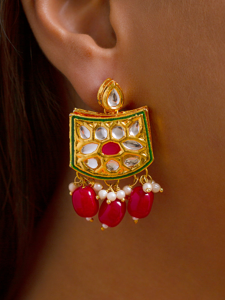 Close-up of a woman wearing an ornate traditional (Gold Polish) Red Choker jewellery set and earrings with Pearl, Crystal stones, Kundan, Colored Stones and Tumble Beads. Mehendi ceremony look completed with a handcrafted Kundan jewelry set. Wedding celebration look enhanced with a statement Kundan necklace.