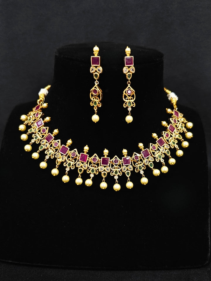 Close-up of an ornate traditional (Gold Polish) Pink jewellery set and earrings with Pearls and Colored Stones. Festive saree styling with a premium artificial Colored Stones necklace. Mehendi ceremony look completed with a handcrafted Colored Stones jewelry set.