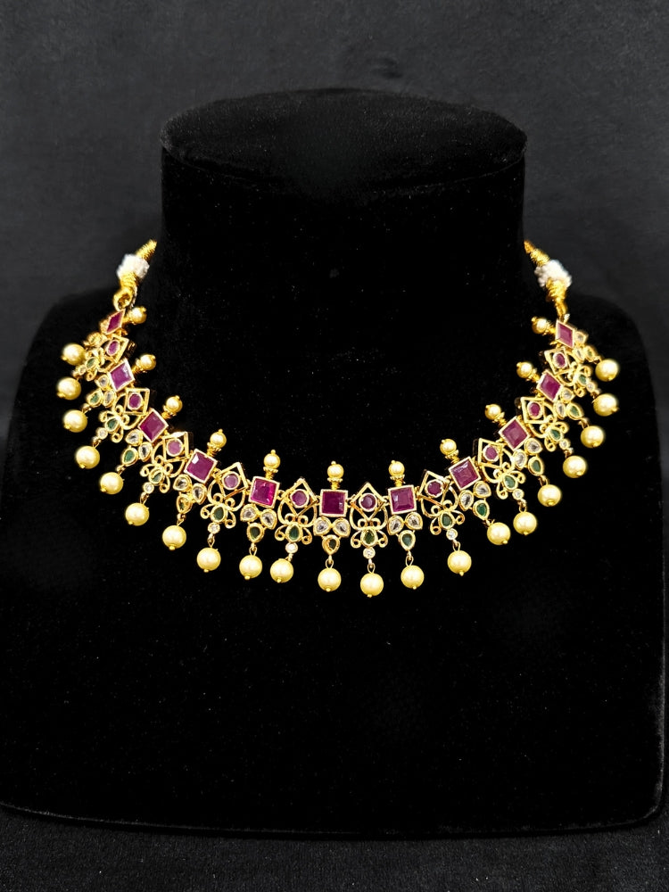 Close-up of an ornate traditional (Gold Polish) Pink jewellery set and earrings with Pearls and Colored Stones. Festive saree styling with a premium artificial Colored Stones necklace. Mehendi ceremony look completed with a handcrafted Colored Stones jewelry set.