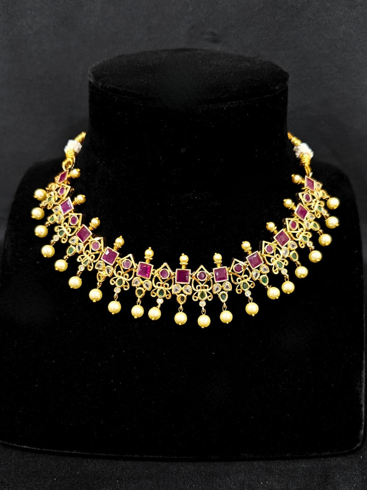Close-up of an ornate traditional (Gold Polish) Pink jewellery set and earrings with Pearls and Colored Stones. Festive saree styling with a premium artificial Colored Stones necklace. Mehendi ceremony look completed with a handcrafted Colored Stones jewelry set.