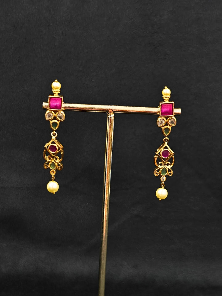 Close-up of an ornate traditional (Gold Polish) Pink jewellery set and earrings with Pearls and Colored Stones. Festive saree styling with a premium artificial Colored Stones necklace. Mehendi ceremony look completed with a handcrafted Colored Stones jewelry set.