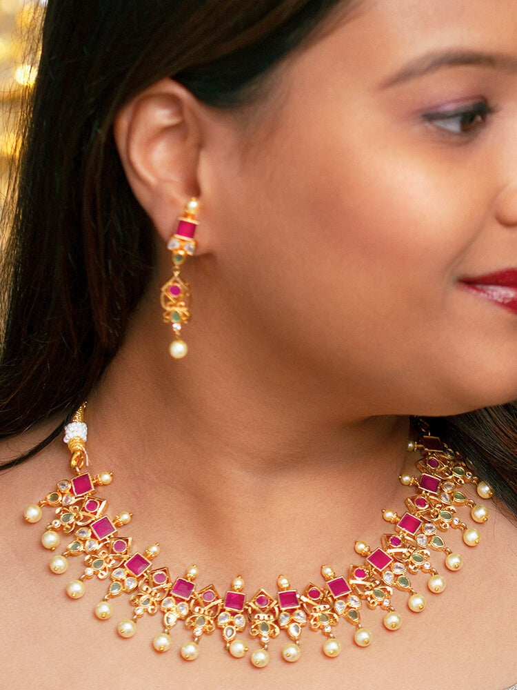Close-up of a woman wearing an ornate traditional (Gold Polish) Pink jewellery set and earrings with Pearls and Colored Stones. Festive saree styling with a premium artificial Colored Stones necklace. Mehendi ceremony look completed with a handcrafted Colored Stones jewelry set.