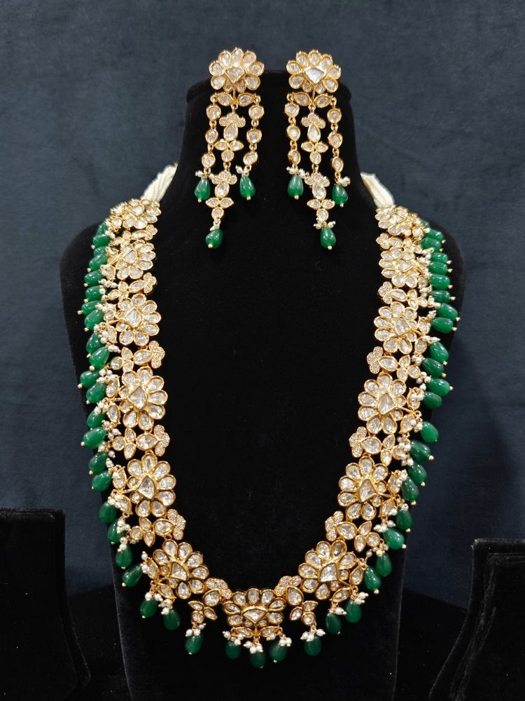 Close-up of an ornate traditional (Gold Polish) Long jewellery set and earrings with Polki, American Diamond Tumble Beads and Pearls. Wedding guest outfit styled with an elegant Polki necklace set. Woman Bridal mehendi outfit paired with a royal Polki artificial jewelry set. wearing trending Polki artificial jewelry for the wedding season in India. 