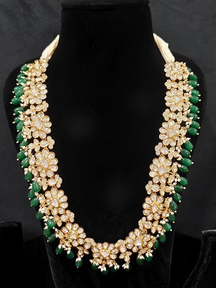 Close-up of an ornate traditional (Gold Polish) Long jewellery set and earrings with Polki, American Diamond Tumble Beads and Pearls. Wedding guest outfit styled with an elegant Polki necklace set. Woman Bridal mehendi outfit paired with a royal Polki artificial jewelry set. wearing trending Polki artificial jewelry for the wedding season in India. 
