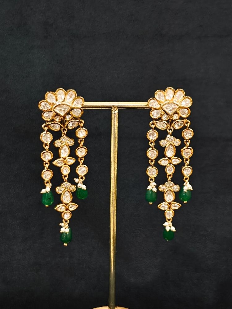 Close-up of an ornate traditional (Gold Polish) Long jewellery set and earrings with Polki, American Diamond Tumble Beads and Pearls. Wedding guest outfit styled with an elegant Polki necklace set. Woman Bridal mehendi outfit paired with a royal Polki artificial jewelry set. wearing trending Polki artificial jewelry for the wedding season in India. 