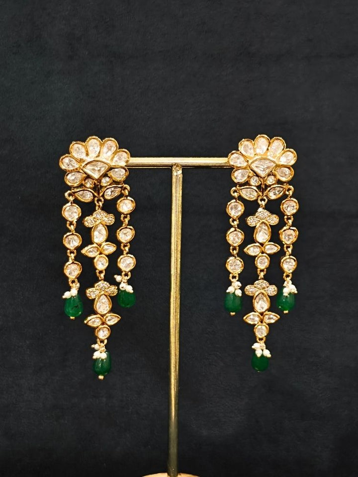 Close-up of an ornate traditional (Gold Polish) Long jewellery set and earrings with Polki, American Diamond Tumble Beads and Pearls. Wedding guest outfit styled with an elegant Polki necklace set. Woman Bridal mehendi outfit paired with a royal Polki artificial jewelry set. wearing trending Polki artificial jewelry for the wedding season in India. 