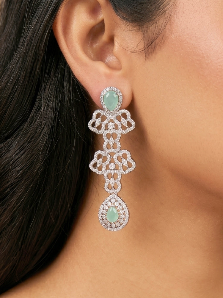 Close-up of a women wearing an ornate Western (Silver Polish) Collar Layered jewellery set and earrings with American Diamond and Mint Green Colored Stones. Reception-ready look featuring a statement American diamond jewelry set. Elegant wedding jewelry look featuring a premium artificial American diamond necklace. 