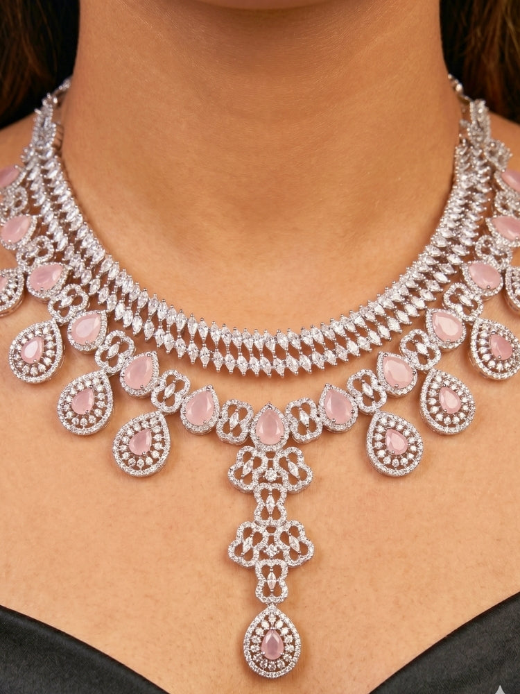 Close-up of a women wearing an ornate Western (Silver Polish) Collar Layered jewellery set and earrings with American Diamond and Mint Pink Colored Stones. Reception-ready look featuring a statement American diamond jewelry set. Elegant wedding jewelry look featuring a premium artificial American diamond necklace.