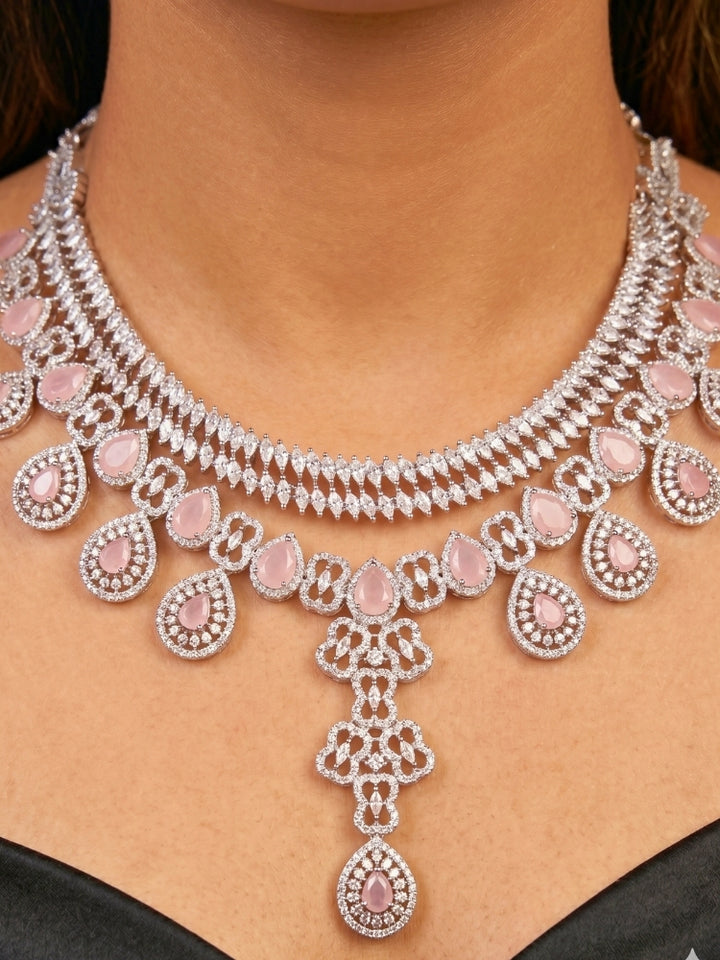 Close-up of a women wearing an ornate Western (Silver Polish) Collar Layered jewellery set and earrings with American Diamond and Mint Pink Colored Stones. Reception-ready look featuring a statement American diamond jewelry set. Elegant wedding jewelry look featuring a premium artificial American diamond necklace.