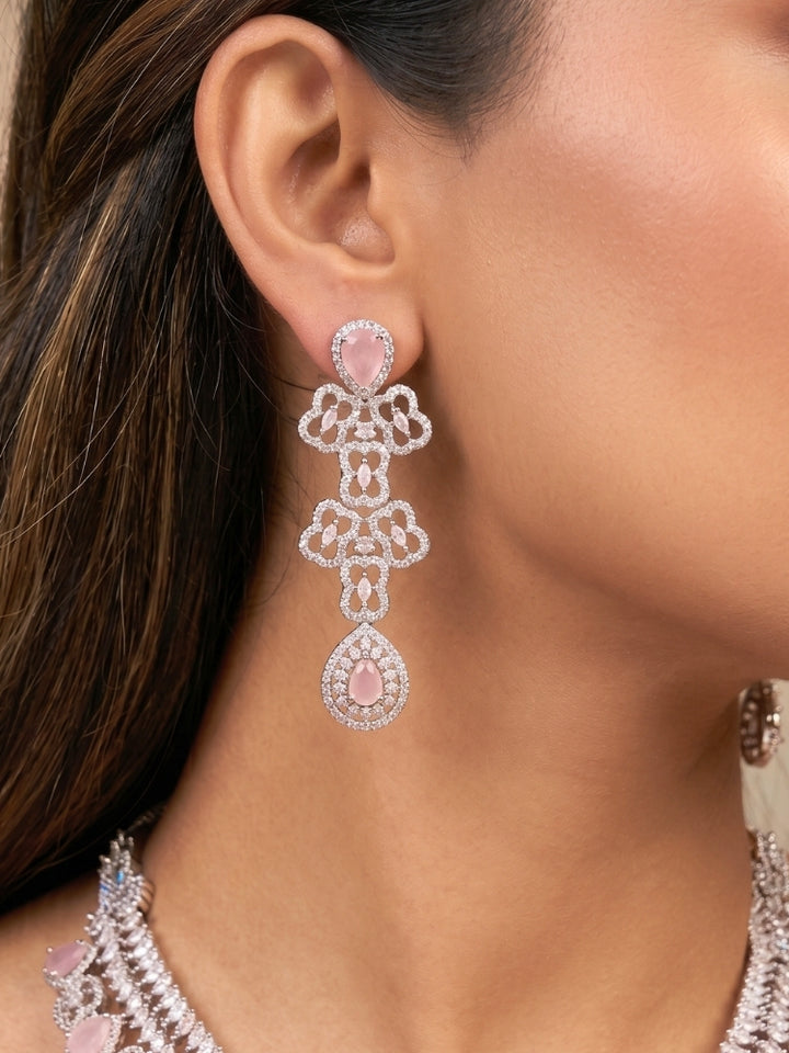 Close-up of a women wearing an ornate Western (Silver Polish) Collar Layered jewellery set and earrings with American Diamond and Mint Pink Colored Stones. Reception-ready look featuring a statement American diamond jewelry set. Elegant wedding jewelry look featuring a premium artificial American diamond necklace.