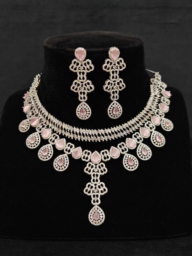 Close-up of an ornate Western (Silver Polish) Collar Layered jewellery set and earrings with American Diamond and Mint Pink Colored Stones. Reception-ready look featuring a statement American diamond jewelry set. Elegant wedding jewelry look featuring a premium artificial American diamond necklace.