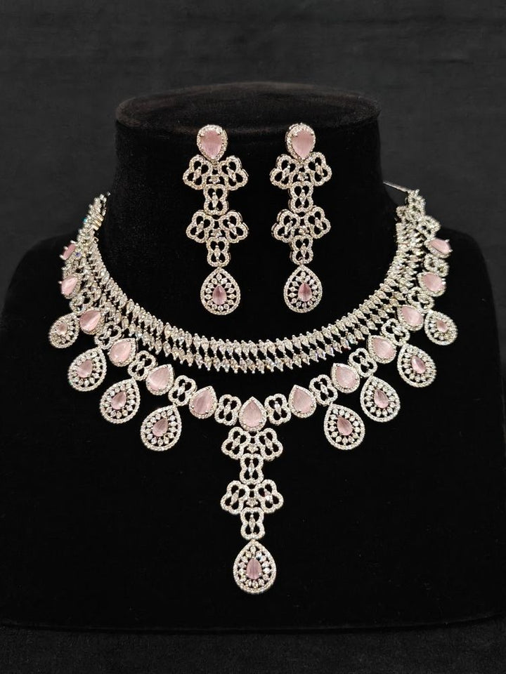 Close-up of an ornate Western (Silver Polish) Collar Layered jewellery set and earrings with American Diamond and Mint Pink Colored Stones. Reception-ready look featuring a statement American diamond jewelry set. Elegant wedding jewelry look featuring a premium artificial American diamond necklace.
