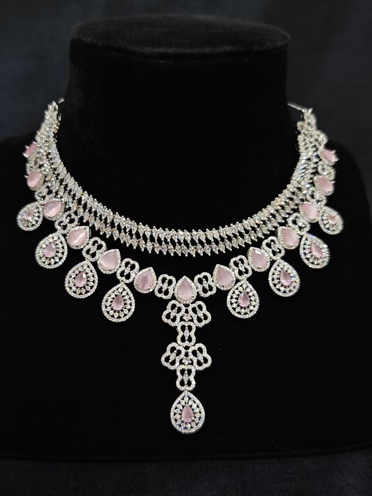 Close-up of an ornate Western (Silver Polish) Collar Layered jewellery set and earrings with American Diamond and Mint Pink Colored Stones. Reception-ready look featuring a statement American diamond jewelry set. Elegant wedding jewelry look featuring a premium artificial American diamond necklace.