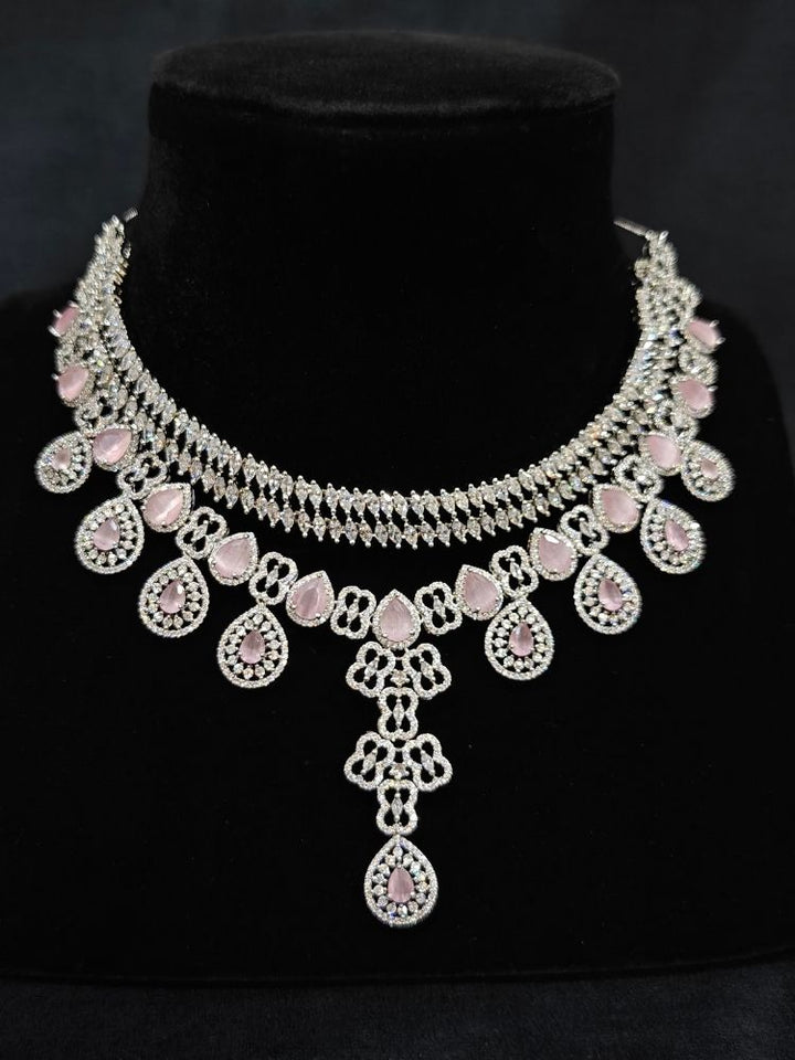 Close-up of an ornate Western (Silver Polish) Collar Layered jewellery set and earrings with American Diamond and Mint Pink Colored Stones. Reception-ready look featuring a statement American diamond jewelry set. Elegant wedding jewelry look featuring a premium artificial American diamond necklace.