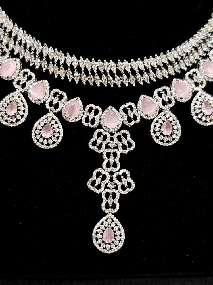 Close-up of an ornate Western (Silver Polish) Collar Layered jewellery set and earrings with American Diamond and Mint Pink Colored Stones. Reception-ready look featuring a statement American diamond jewelry set. Elegant wedding jewelry look featuring a premium artificial American diamond necklace.