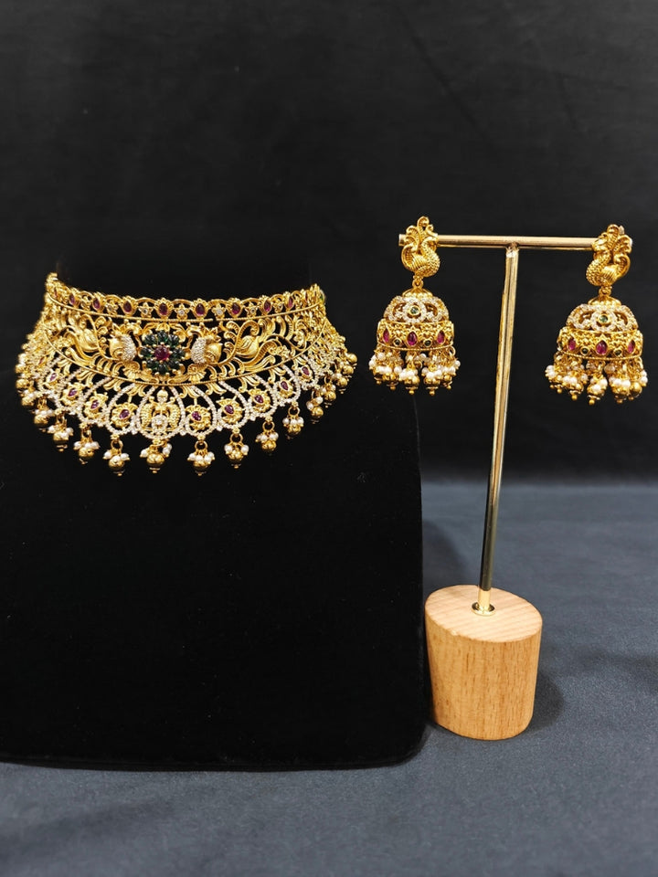 Close-up of an ornate traditional Heritage gold Choker jewellery set and earrings with Pota Stone and American Diamond. Wedding guest look featuring a traditional heritage artificial necklace. Close-up of antique-style detailing in heritage artificial jewelry.