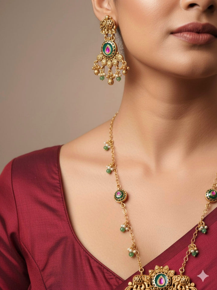 Close-up of a woman wearing an ornate traditional Green Heritage gold jewellery set and earrings with Mint Green Colored Stones, Beads. Festive Diwali outfit styled with a royal heritage necklace. Festive look completed with a luxury Heritage imitation necklace.
