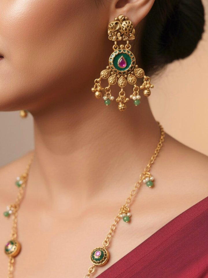 Close-up of a woman wearing an ornate traditional Green Heritage gold jewellery set and earrings with Mint Green Colored Stones, Beads. Festive Diwali outfit styled with a royal heritage necklace. Festive look completed with a luxury Heritage imitation necklace.
