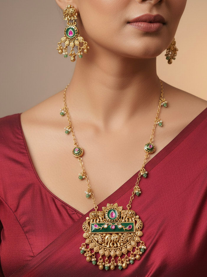 Close-up of a woman wearing an ornate traditional Green Heritage gold jewellery set and earrings with Mint Green Colored Stones, Beads. Festive Diwali outfit styled with a royal heritage necklace. Festive look completed with a luxury Heritage imitation necklace.
