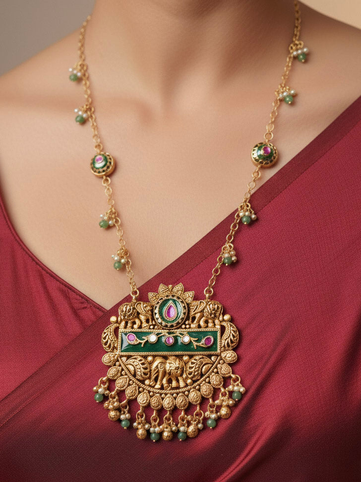 Close-up of a woman wearing an ornate traditional Green Heritage gold jewellery set and earrings with Mint Green Colored Stones, Beads. Festive Diwali outfit styled with a royal heritage necklace. Festive look completed with a luxury Heritage imitation necklace.
