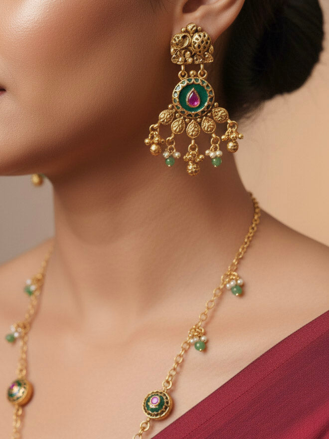Close-up of a woman wearing an ornate traditional Green Heritage gold jewellery set and earrings with Mint Green Colored Stones, Beads. Festive Diwali outfit styled with a royal heritage necklace. Festive look completed with a luxury Heritage imitation necklace.
