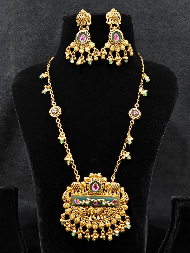 Close-up of an ornate traditional Green Heritage gold jewellery set and earrings with Mint Green Colored Stones, Beads. Festive Diwali outfit styled with a royal heritage necklace. Festive look completed with a luxury Heritage imitation necklace.