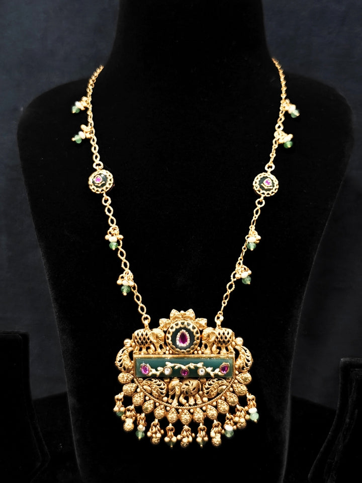 Close-up of an ornate traditional Green Heritage gold jewellery set and earrings with Mint Green Colored Stones, Beads. Festive Diwali outfit styled with a royal heritage necklace. Festive look completed with a luxury Heritage imitation necklace.