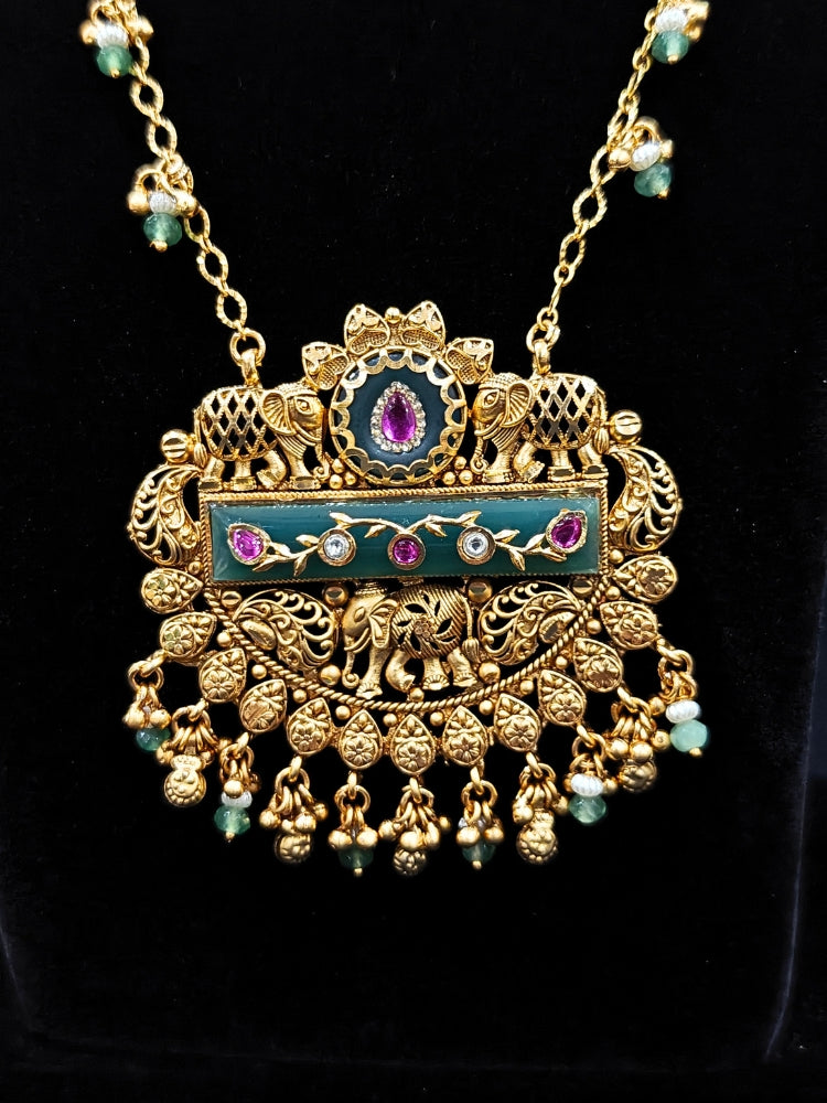 Close-up of an ornate traditional Green Heritage gold jewellery set and earrings with Mint Green Colored Stones, Beads. Festive Diwali outfit styled with a royal heritage necklace. Festive look completed with a luxury Heritage imitation necklace.