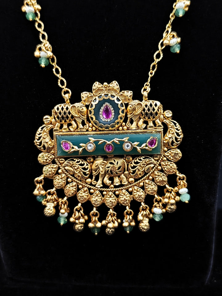 Close-up of an ornate traditional Green Heritage gold jewellery set and earrings with Mint Green Colored Stones, Beads. Festive Diwali outfit styled with a royal heritage necklace. Festive look completed with a luxury Heritage imitation necklace.