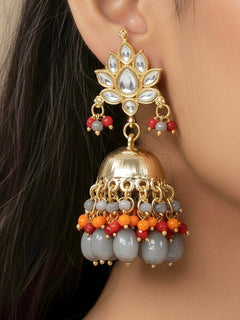 Close-up of a woman wearing an ornate traditional (Gold Polish) Grey Earrings with Kundan Orange, Red & Grey Colored Beads and Grey Tumble Beads. Woman wearing artificial Kundan earrings for a traditional wedding. Festive saree look completed with premium imitation Kundan earrings.