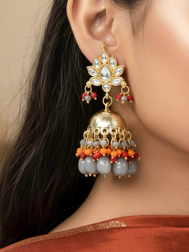 Close-up of a woman wearing an ornate traditional (Gold Polish) Grey Earrings with Kundan Orange, Red & Grey Colored Beads and Grey Tumble Beads. Woman wearing artificial Kundan earrings for a traditional wedding. Festive saree look completed with premium imitation Kundan earrings.
