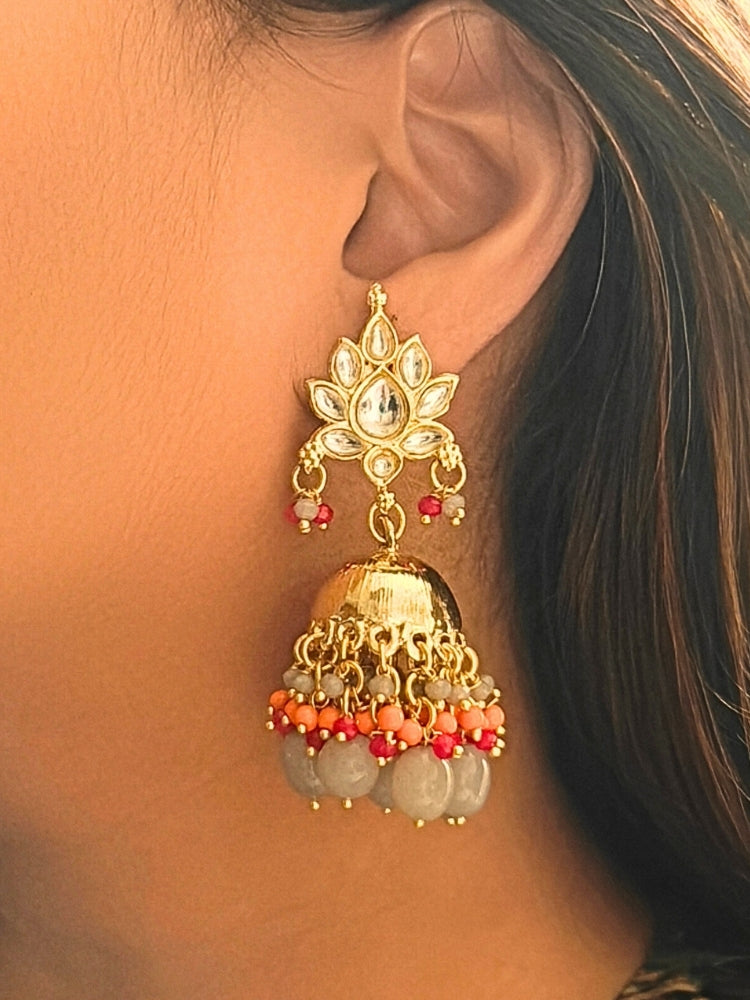 Close-up of a woman wearing an ornate traditional (Gold Polish) Grey Earrings with Kundan Orange, Red & Grey Colored Beads and Grey Tumble Beads. Woman wearing artificial Kundan earrings for a traditional wedding. Festive saree look completed with premium imitation Kundan earrings.