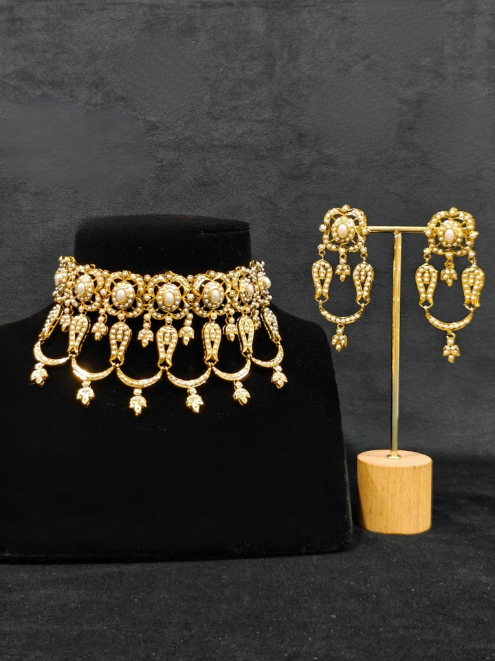 Close-up of an ornate traditional Choker white jadau gold jewellery set and jadau earrings with Pearl. Elegant reception look featuring a luxury Jadau artificial jewelry set. Close-up of high-quality Jadau artificial necklace craftsmanship.