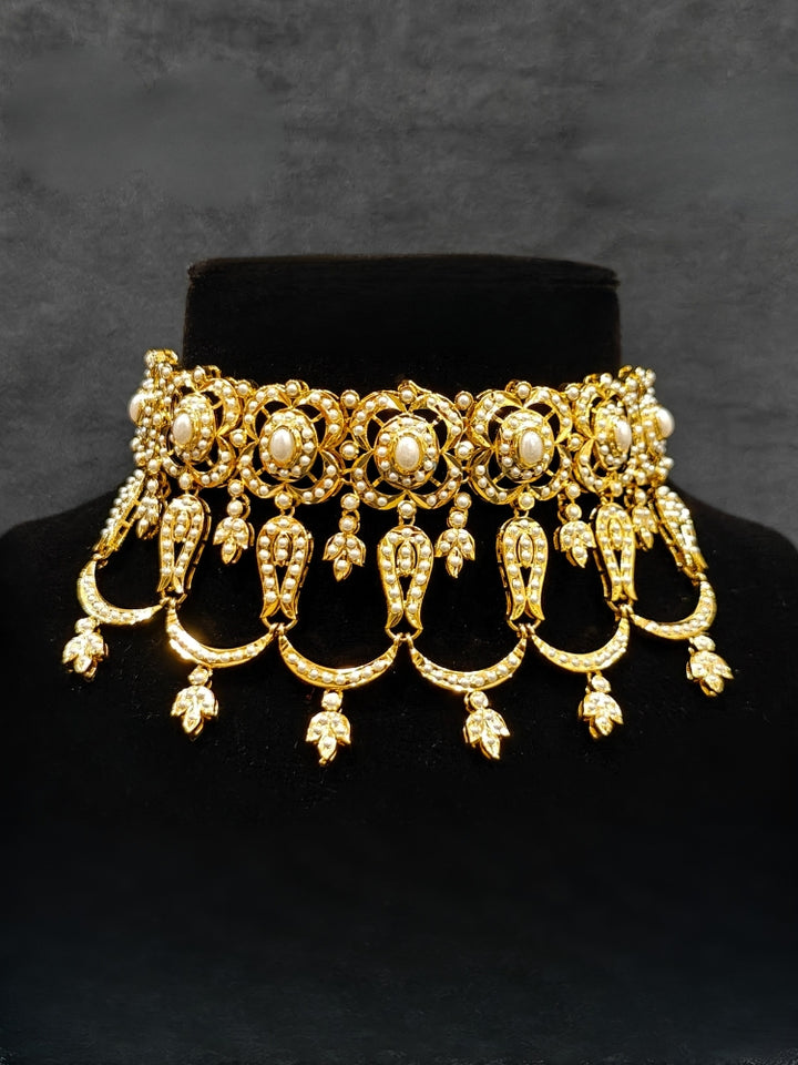 Close-up of an ornate traditional Choker white jadau gold jewellery set and jadau earrings with Pearl. Elegant reception look featuring a luxury Jadau artificial jewelry set. Close-up of high-quality Jadau artificial necklace craftsmanship.